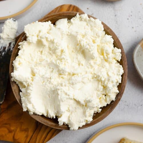 close up picture of a wooden bowl of ricotta cheese little plates of other ingredients
