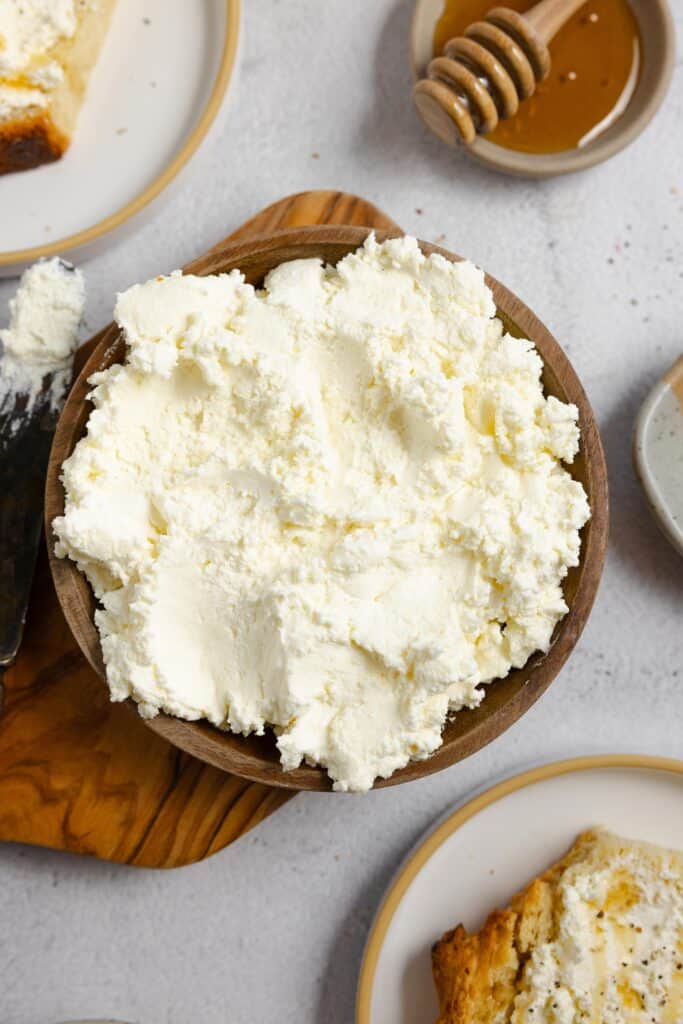 close up picture of a wooden bowl of ricotta cheese little plates of other ingredients