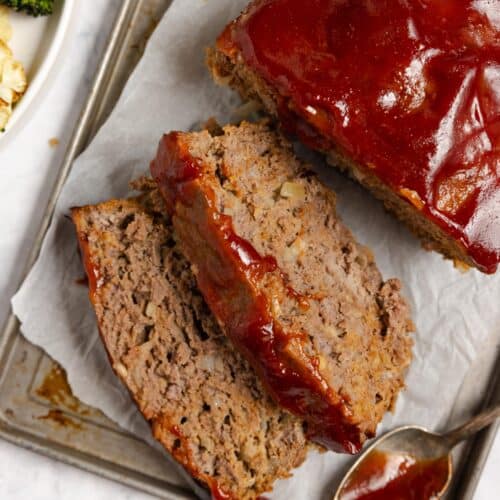 Meatloaf with two pieces sliced from it on a piece of parchment paper