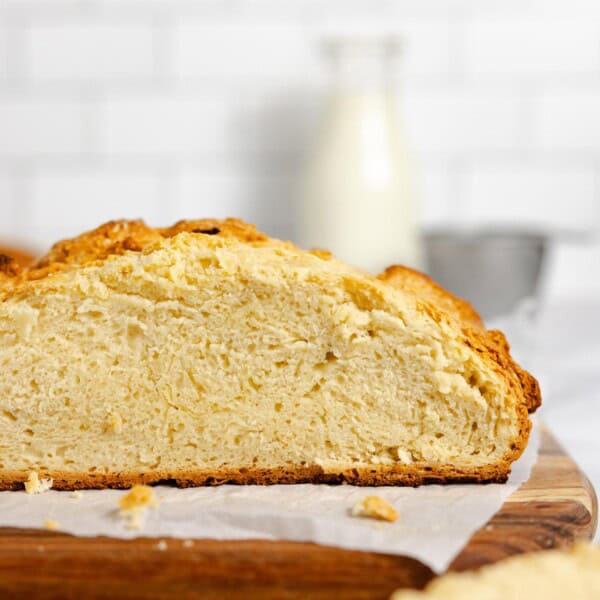 a side view of sourdough Irish bread with a slice taken off on a parchment lined cutting board