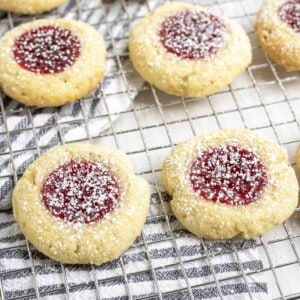 sourdough t thumbprint cookies on a wire rack on top of a black and white stripped towel