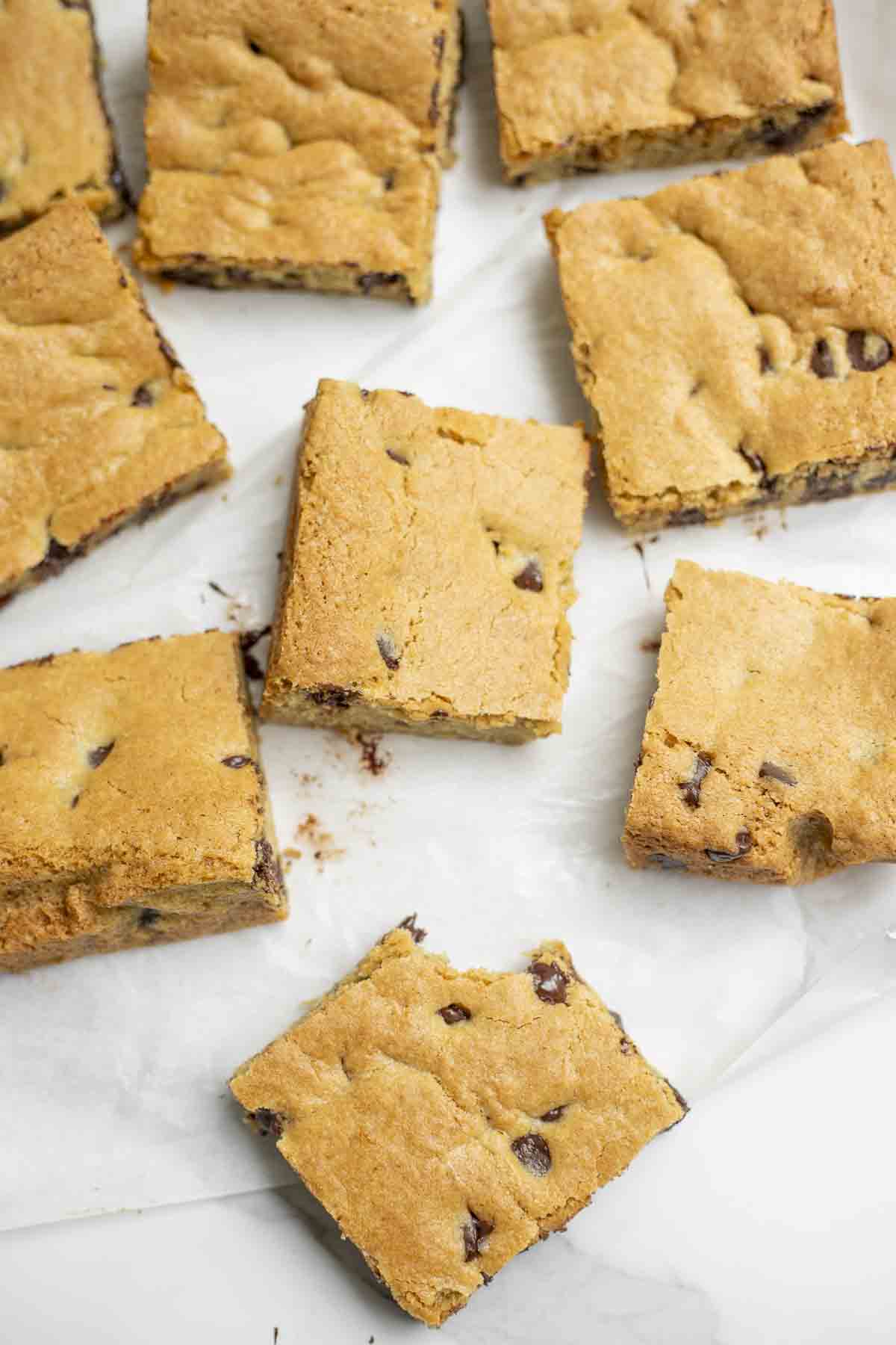 cut squares of chocolate chip blondies on a marble counter top.