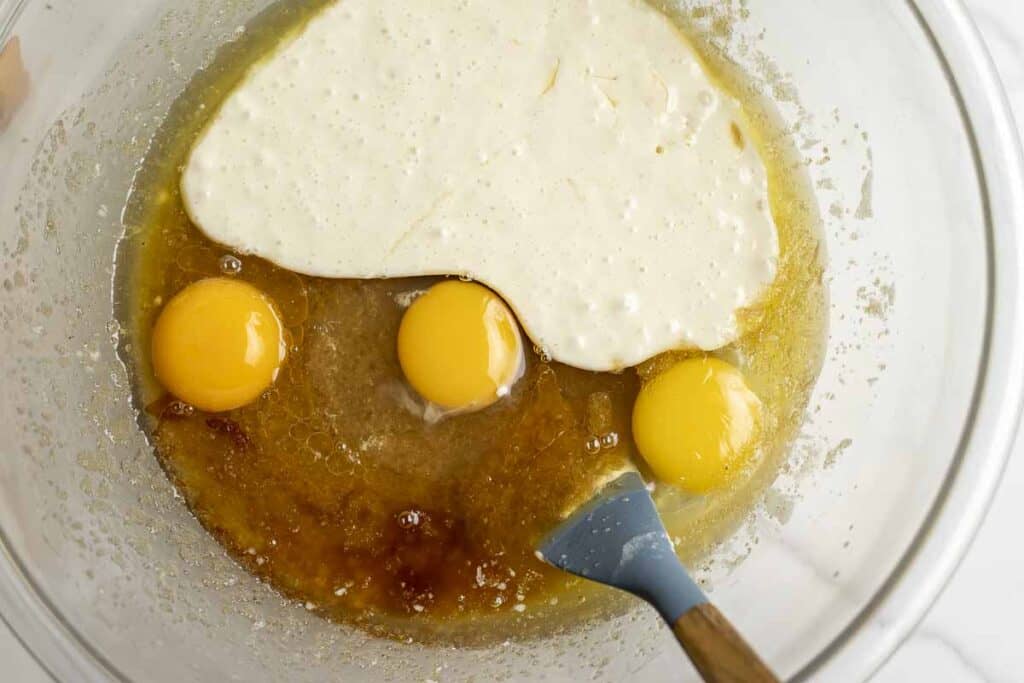 eggs, sourdough starter, and vanilla added to butter and sugar in a glass bowl.
