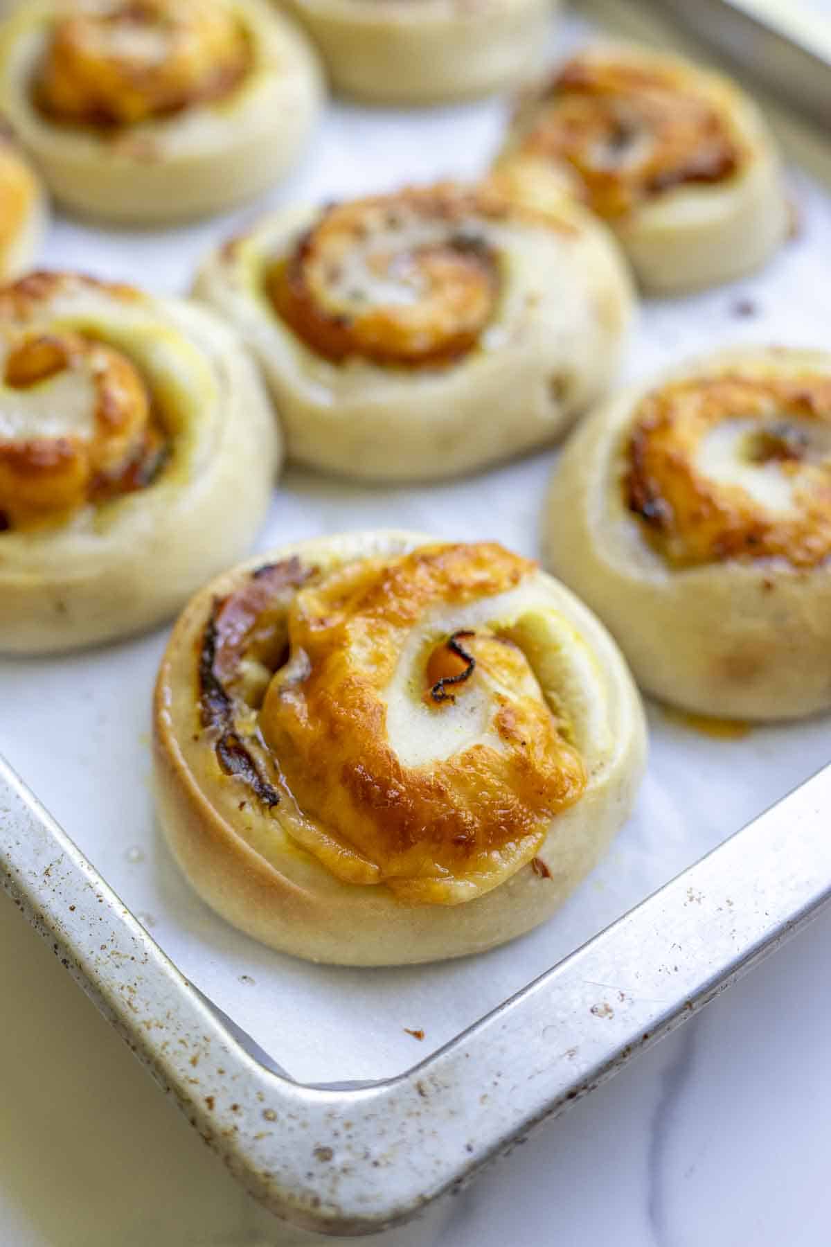 Sourdough ham and cheese rolls fresh out of the oven on a parchment lined baking sheet