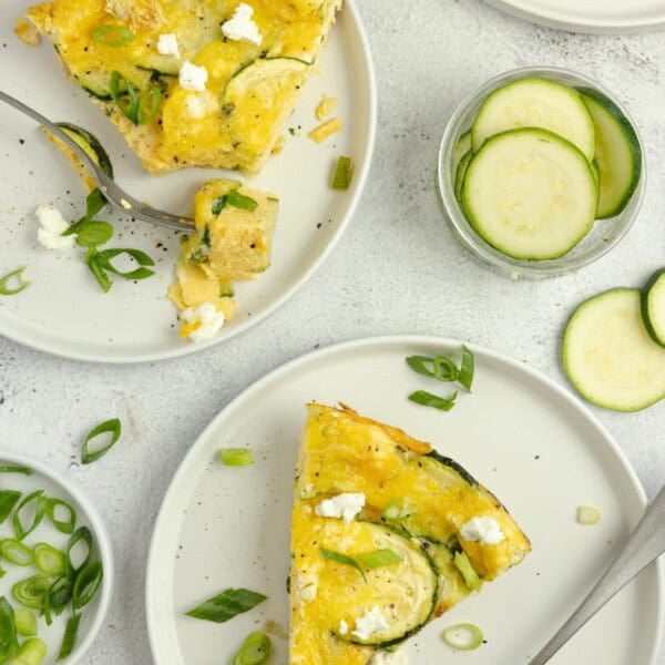 Slices of zucchini frittata on white plates with forks.