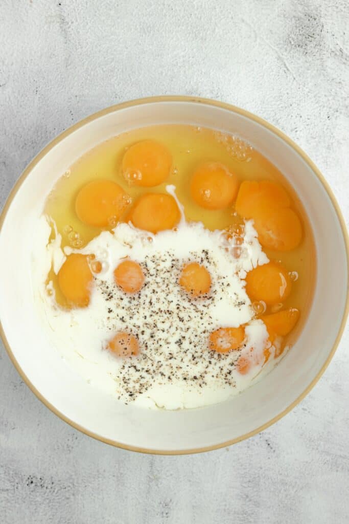 eggs, milk, salt ad pepper in a white bowl.