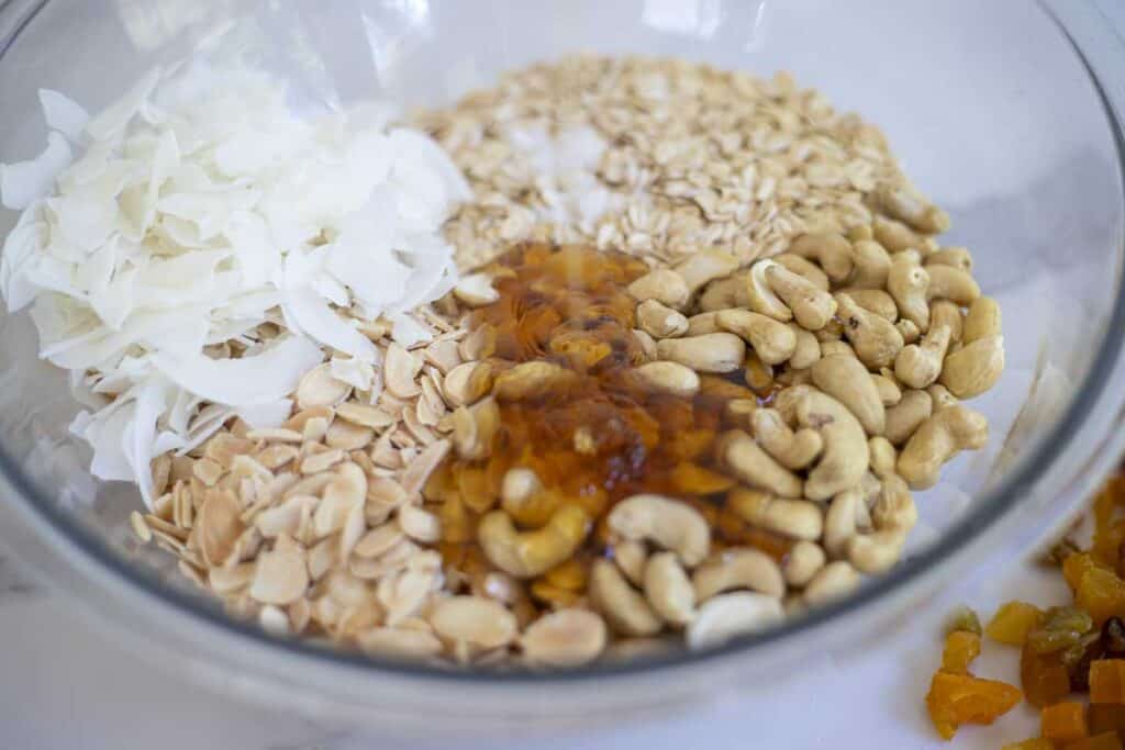 Oats, honey, coconut chips, and nuts in a large bowl.