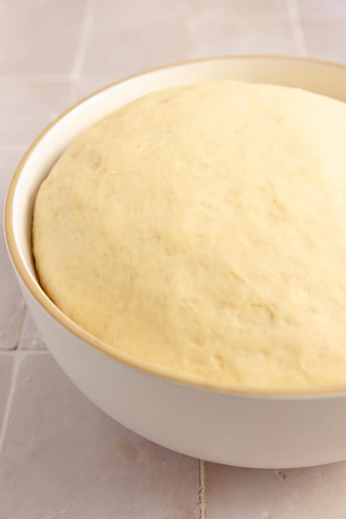 Beignet dough risen in a bowl.