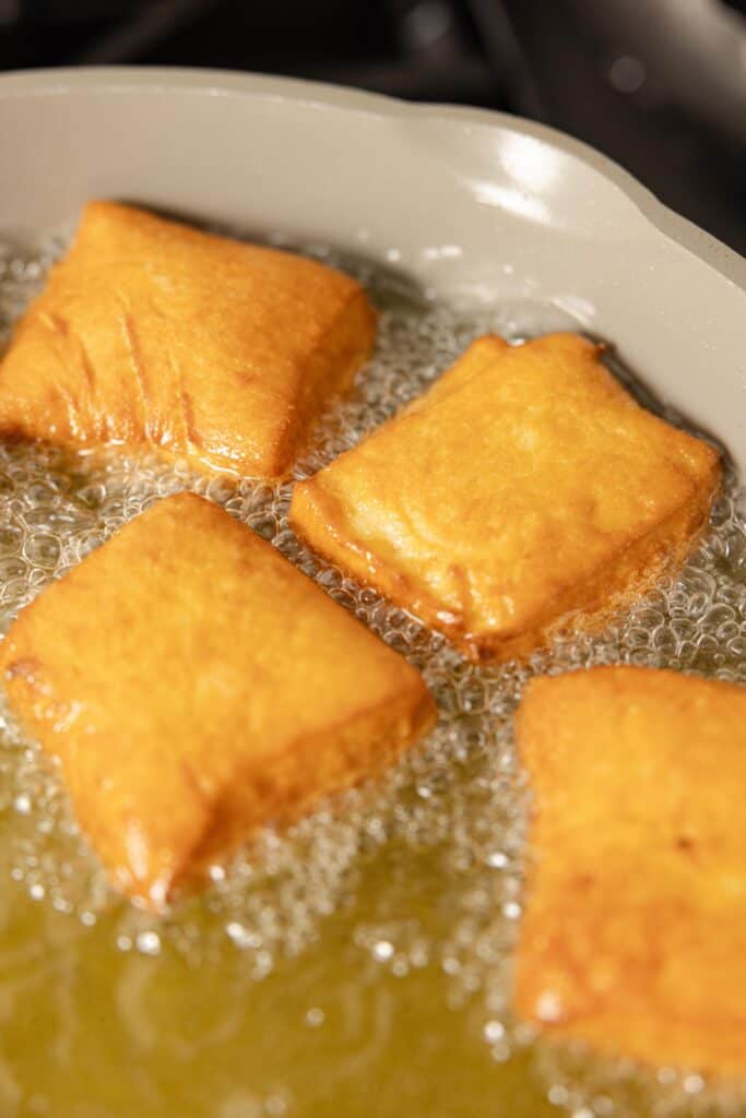 Frying sourdough beignets in oil.