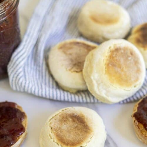 Sourdough discard English muffins on a white and blue striped towel.