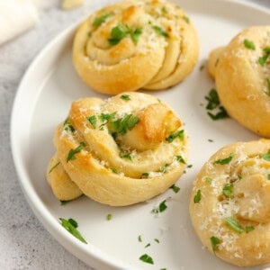 Sourdough garlic knots topped with parsley on a plate.