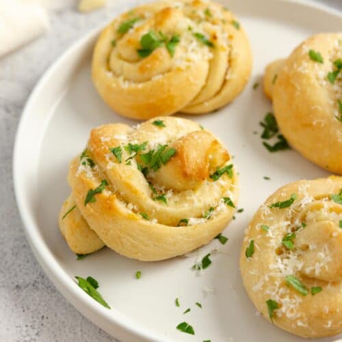 Sourdough garlic knots topped with parsley on a plate.