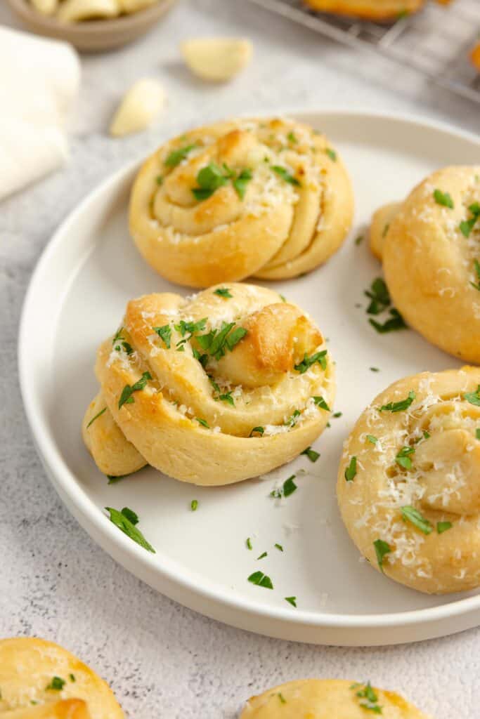 Sourdough garlic knots topped with parsley on a plate.