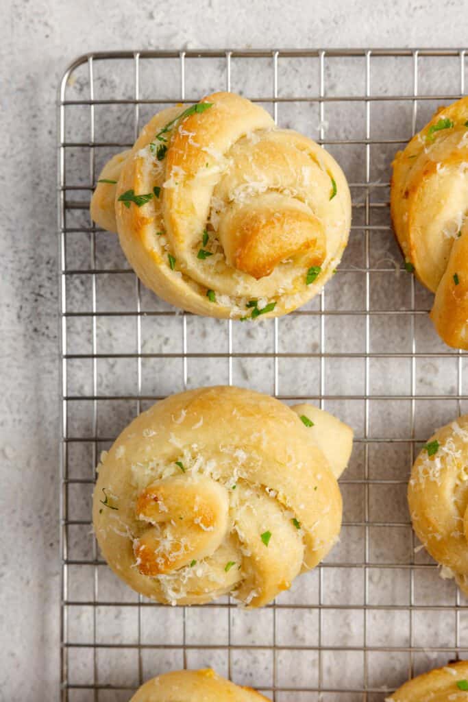 Close up picture of sourdough garlic knots freshly baked and cooling on a wire rack.