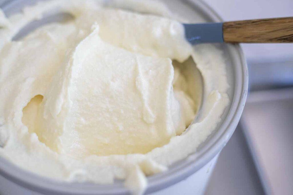 Thick and creamy cheesecake ice cream churned in an ice cream maker bowl.