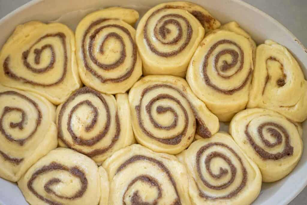 Unbaked cinnamon rolls in a baking pan.