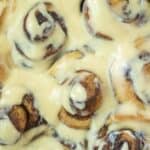 Close up of a pan of sourdough brioche cinnamon rolls topped with cream cheese icing.