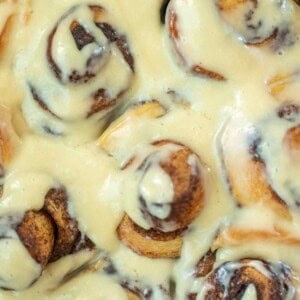 Close up of a pan of sourdough brioche cinnamon rolls topped with cream cheese icing.