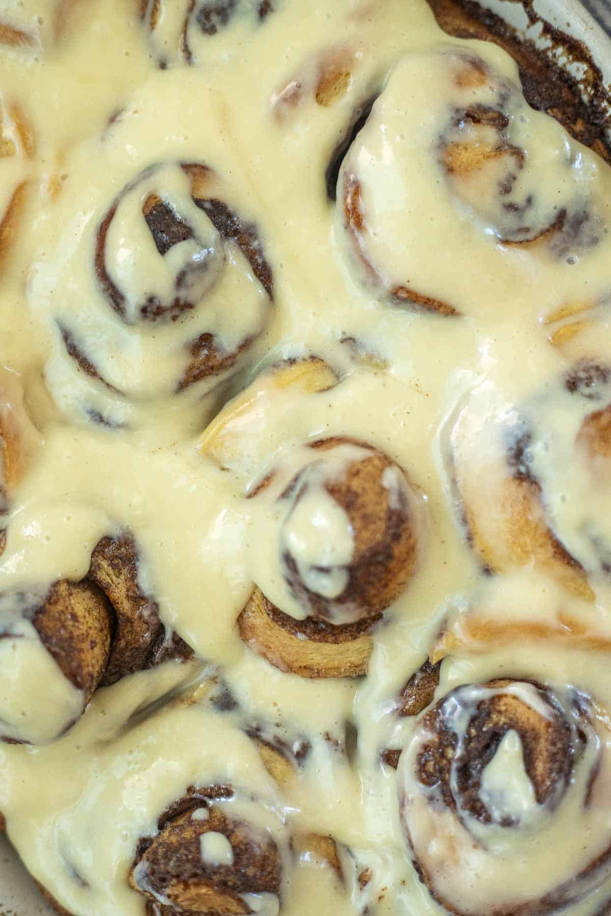 Close up of a pan of sourdough brioche cinnamon rolls topped with cream cheese icing.