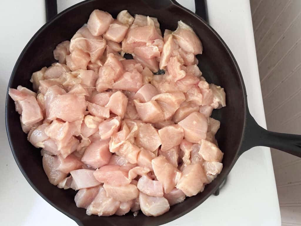 Chicken cooking in a cast iron skillet.