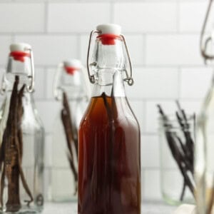 homemade vanilla extract in swing top glass jars on a countertop.