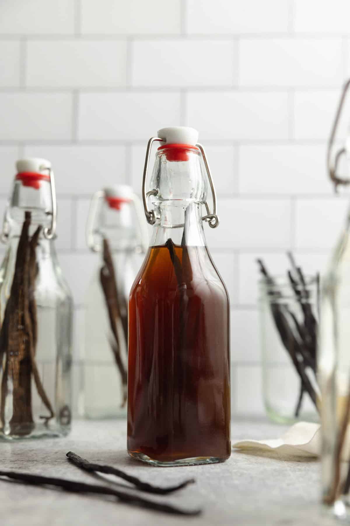 homemade vanilla extract in swing top glass jars on a countertop.