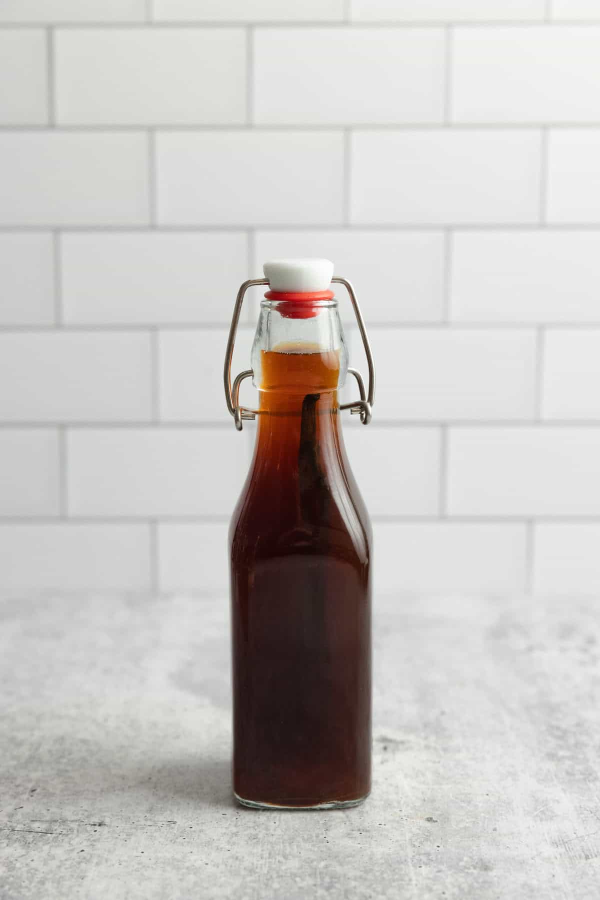 A bottle of homemade vanilla extract on a grey countertop.