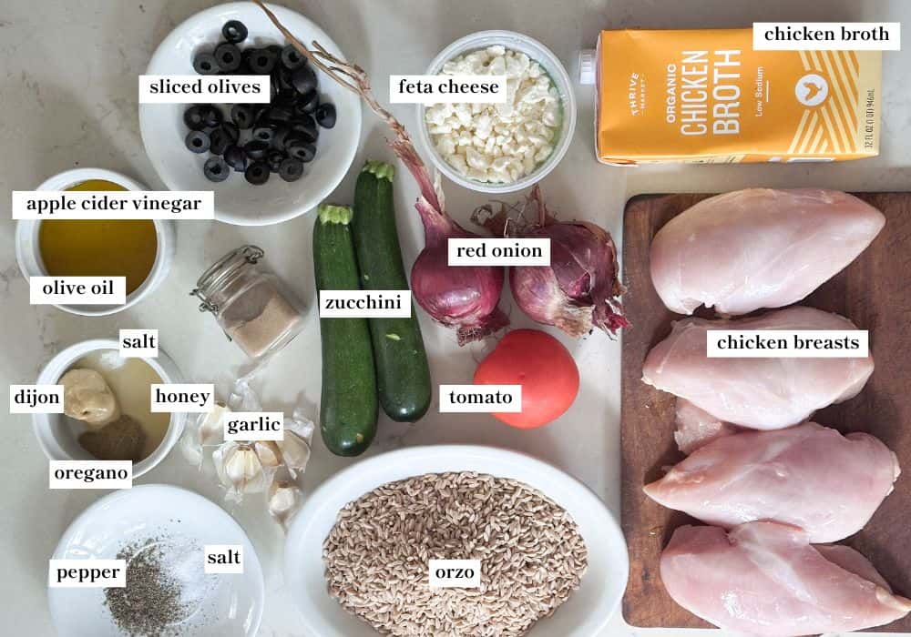 Greek chicken with orzo pasta ingredients laid out on a white countertop. 