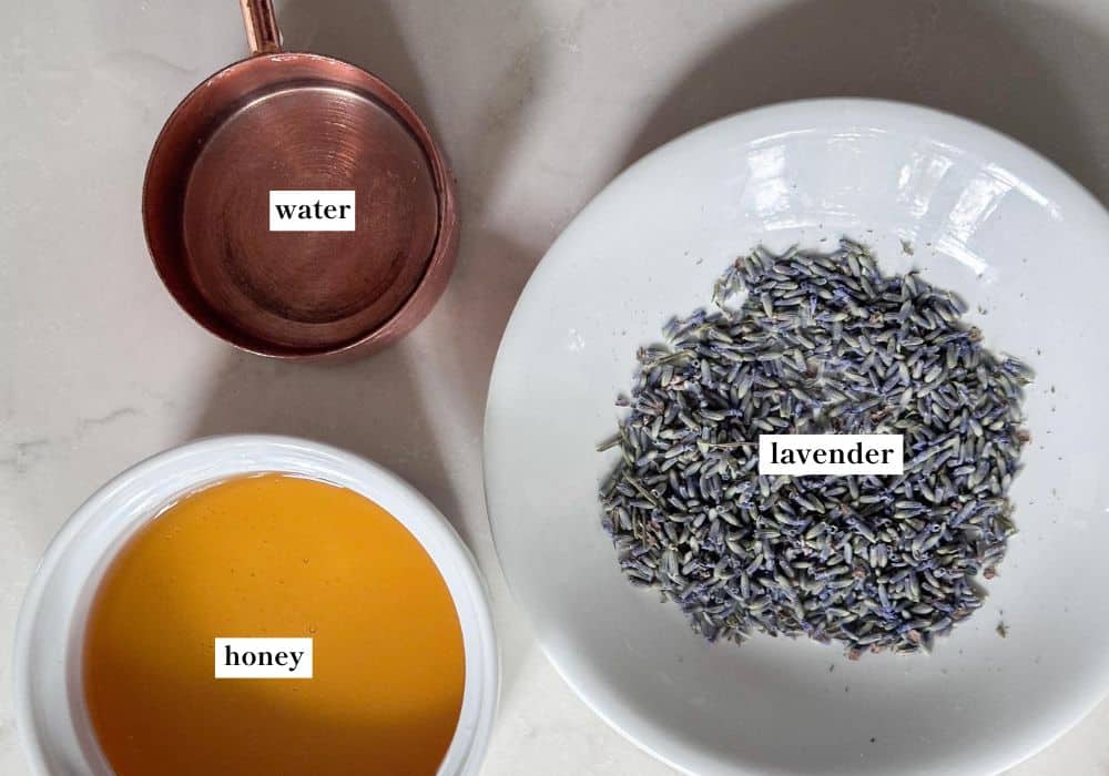 Lavender petals in a bowl, honey in a bowl, and a cup of water.