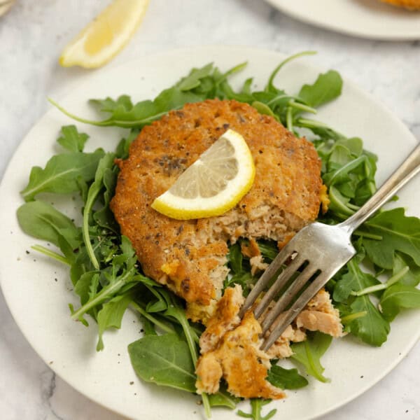 salmon croquettes on a bed of lettuce with a fork taking a biteful out.