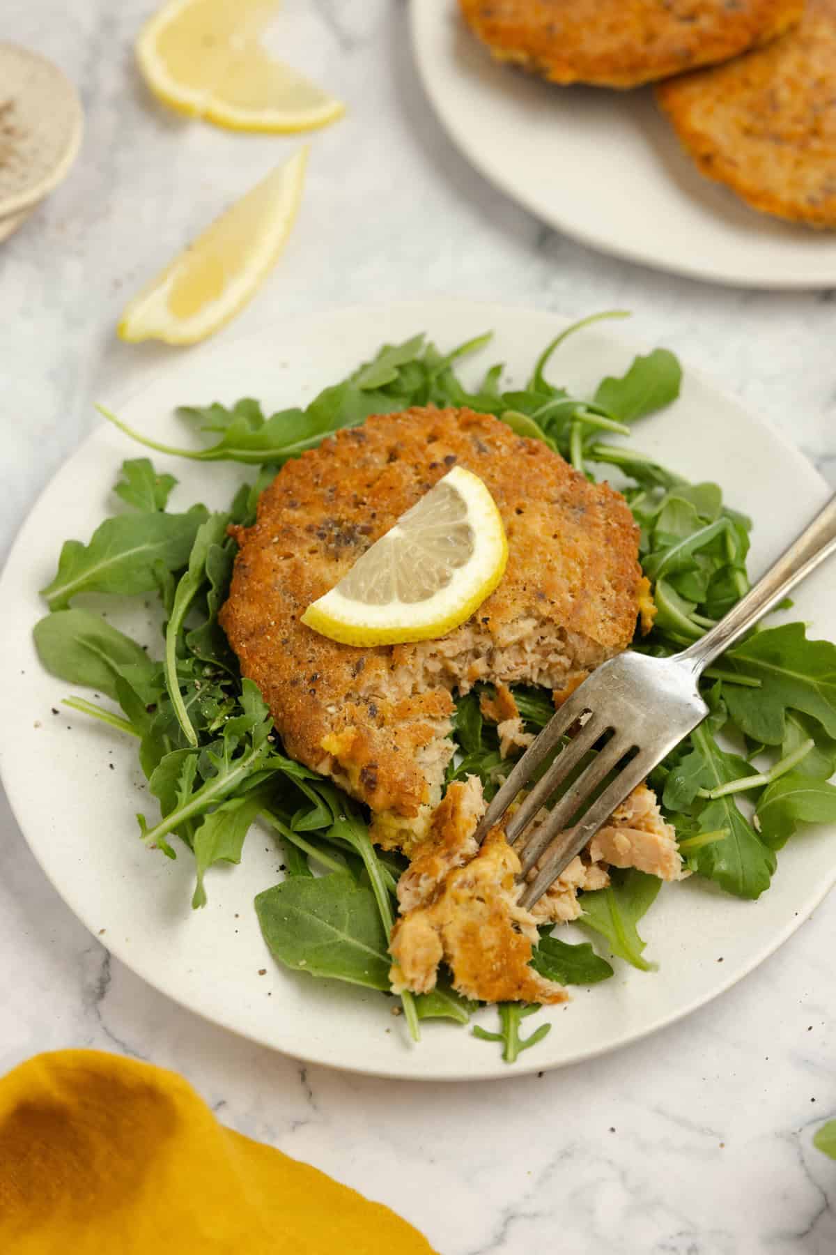 salmon croquettes on a bed of lettuce with a fork taking a biteful out.