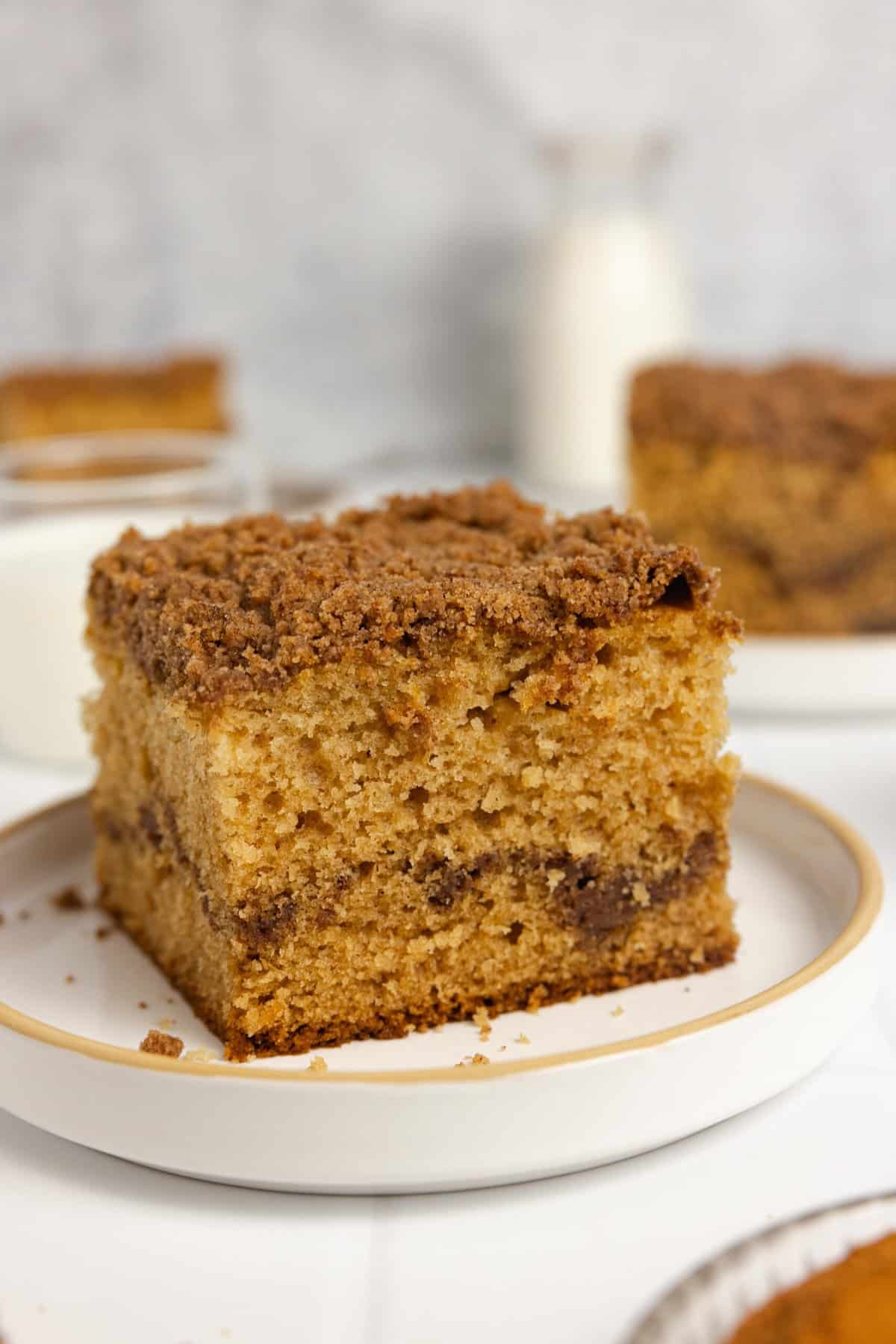 Close up of a large square slice of sourdough coffee cake on a plate with more slices in the background.