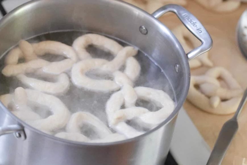 boiling sourdough pretzels in a pot or water.