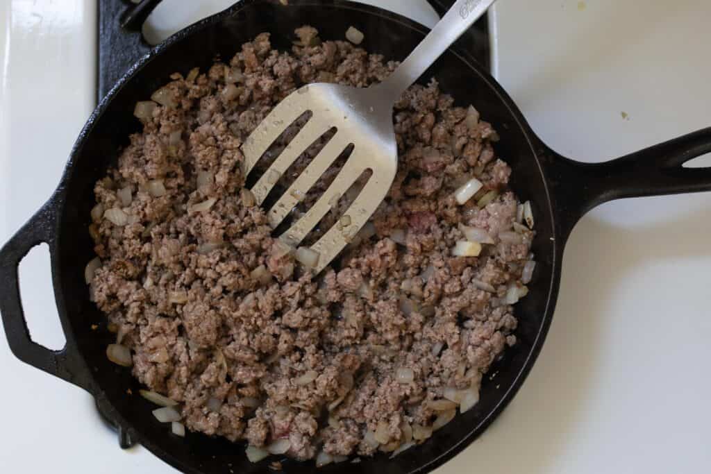 Proud beef and onions in a cast iron skillet.