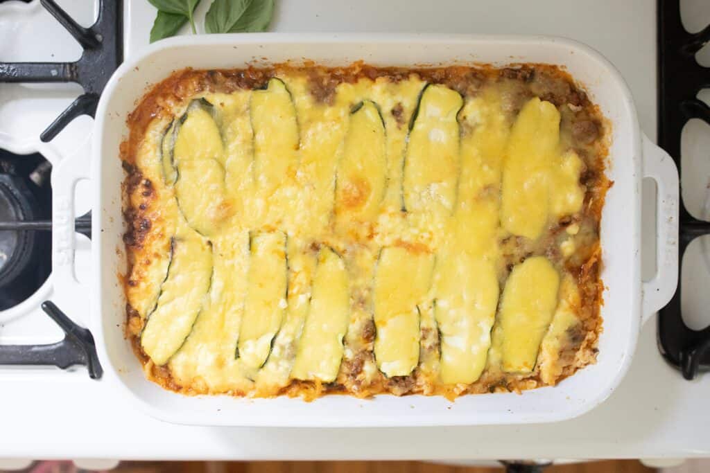 baked zucchini lasagna in a white baking dish on a stove.