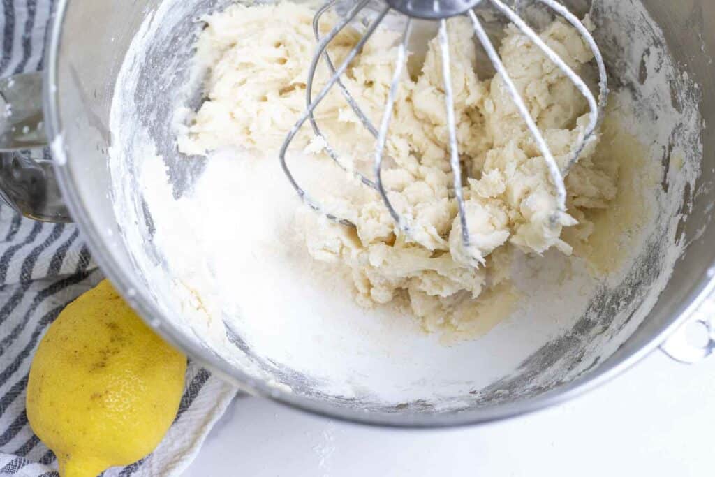 adding powdered sugar to butter in a stank mixer.