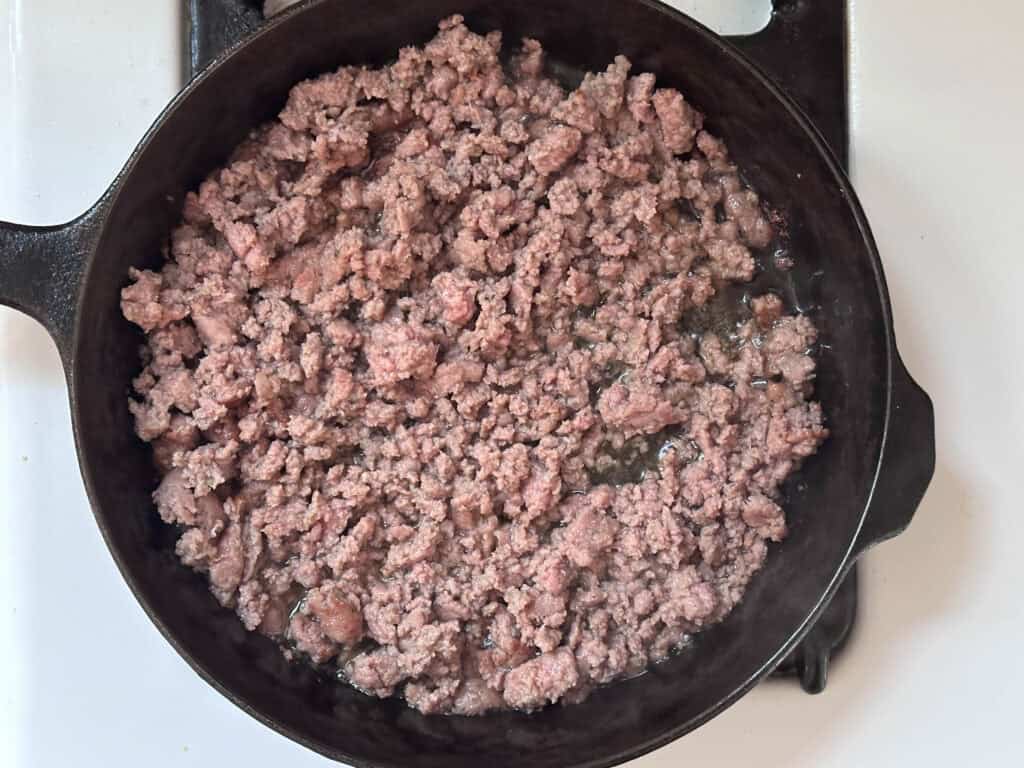 Sausage cooking in a cast iron skillet.