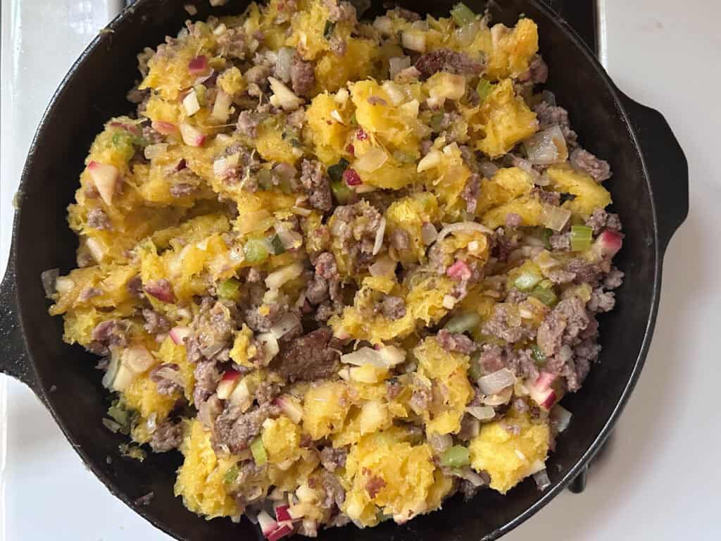 The filled for stuffed acorn squash in a cast iron skillet.