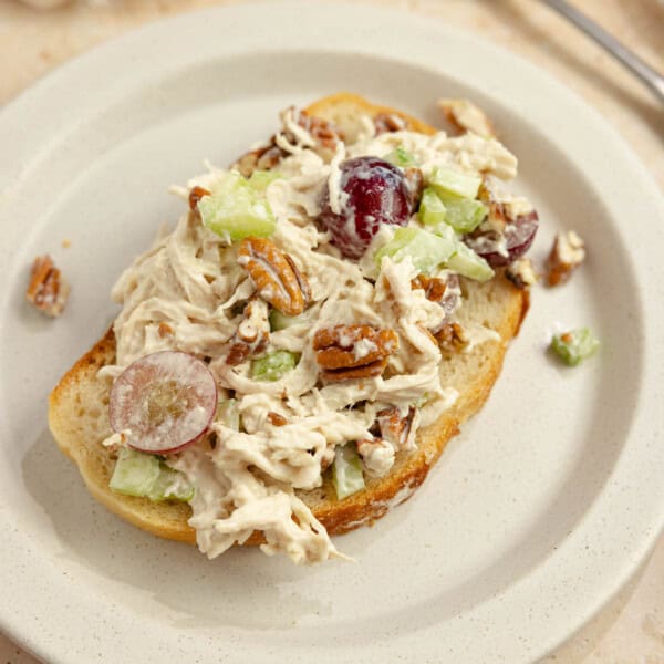 Grape chicken salad on a slice of sourdough bread on a white plate.