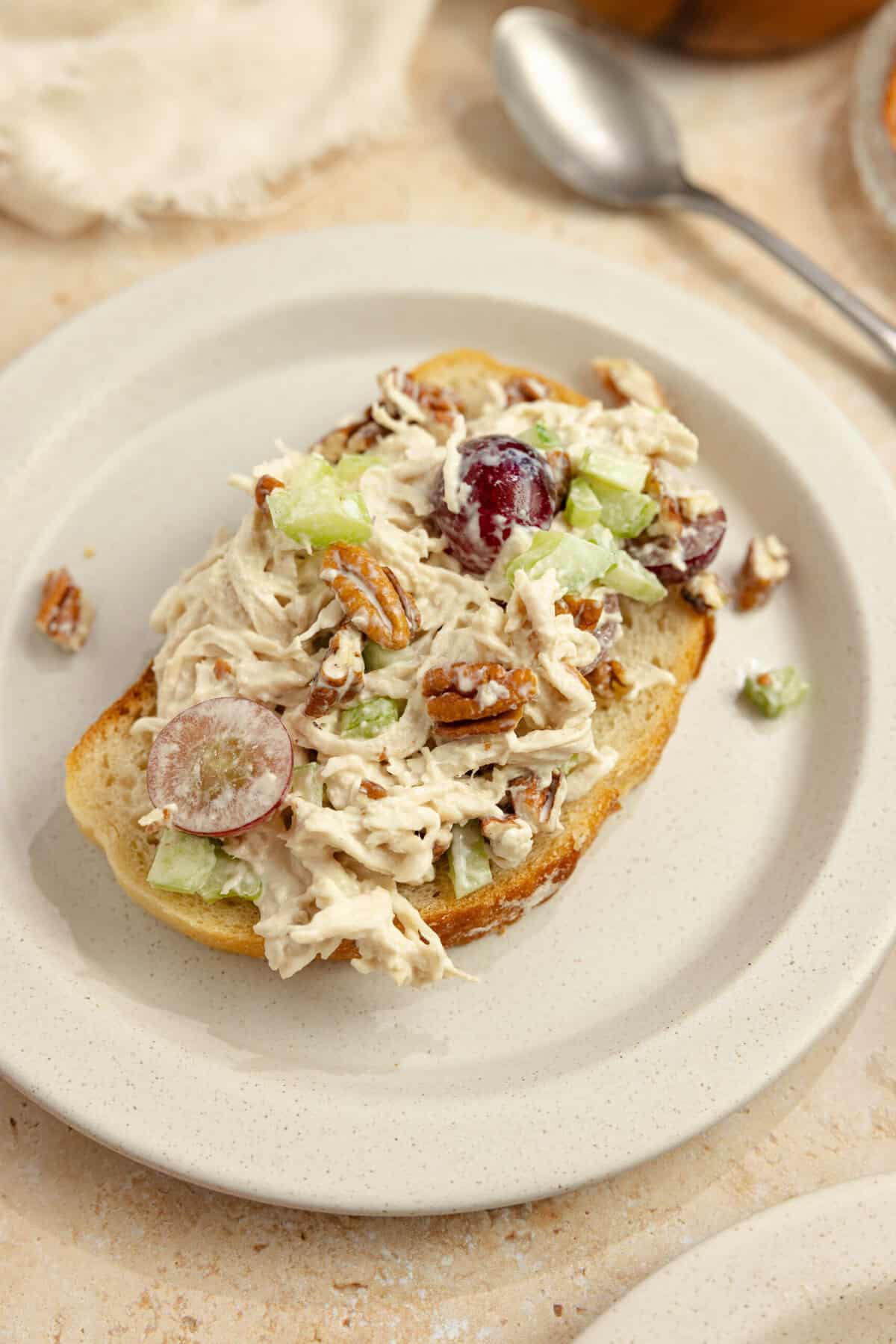 Grape chicken salad on a slice of sourdough bread on a white plate. 