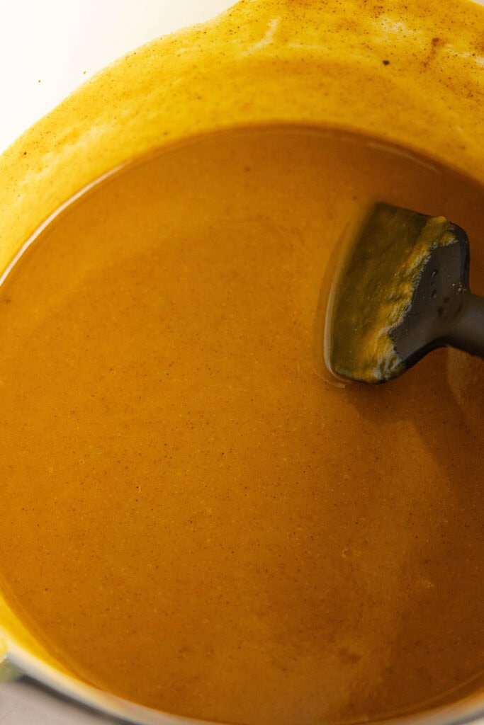 Pumpkin pie spice sauce for a latte stirred with a wooden spoon in a saucepan. 