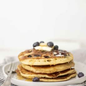 side view of a stack of sourdough blueberry pancakes on a stone plate.