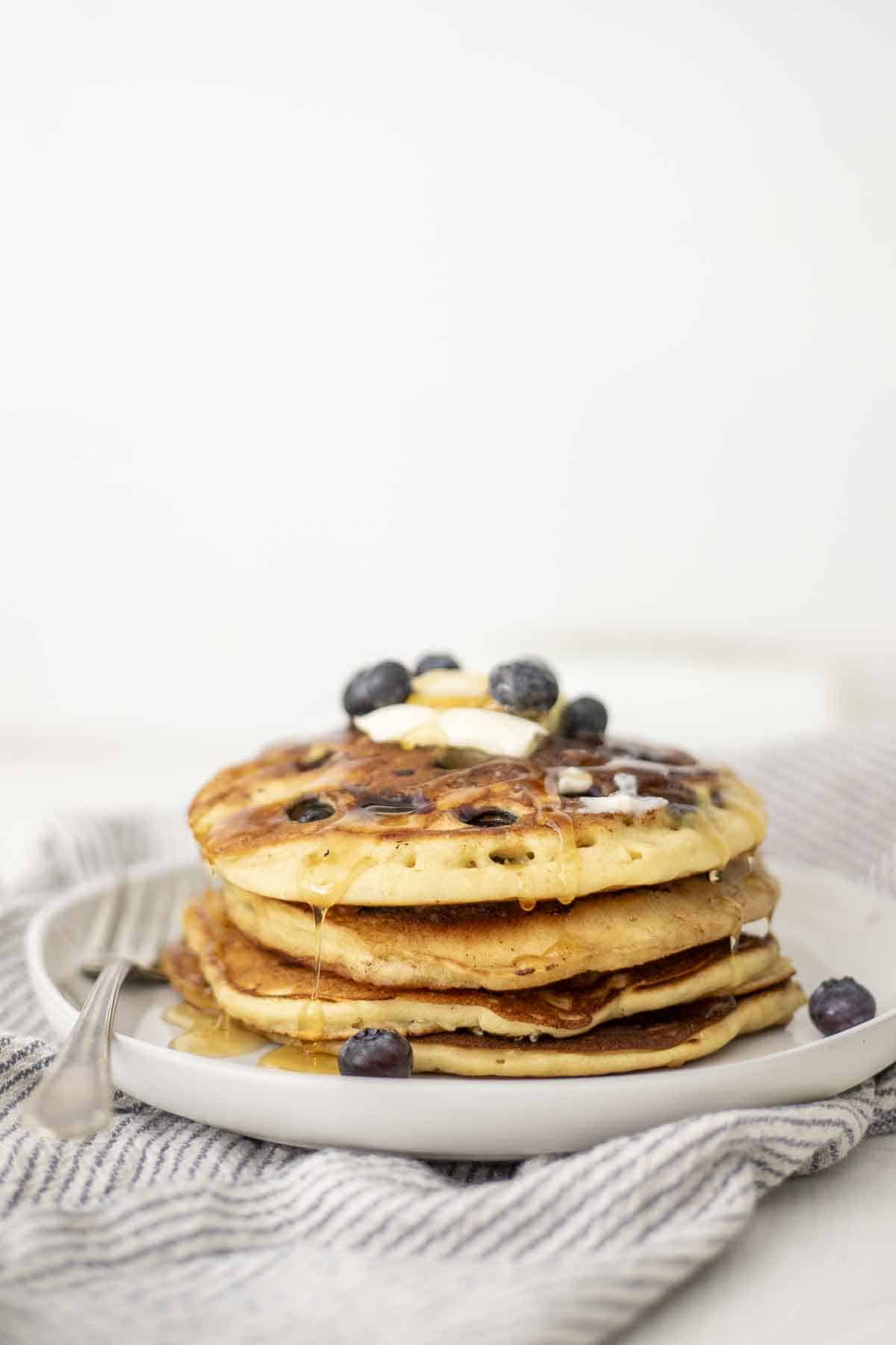 side view of a stack of sourdough blueberry pancakes on a stone plate. 