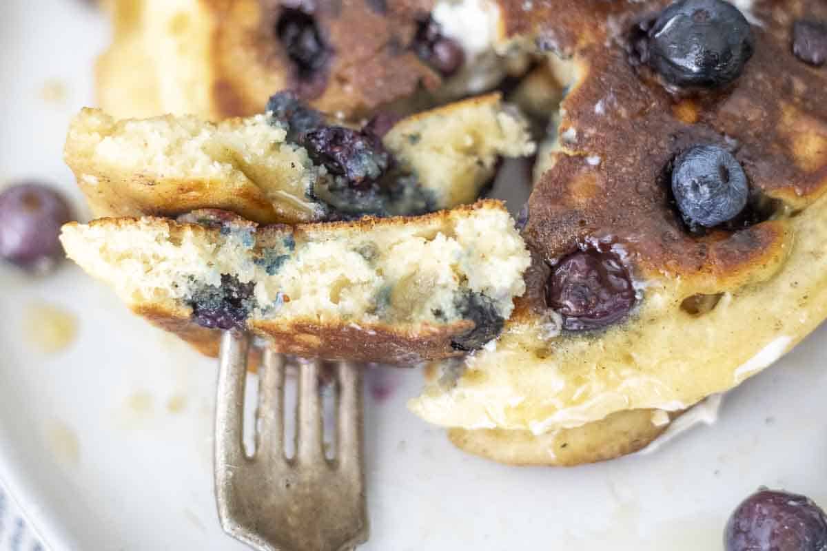 Fluffy sourdough blueberry pancakes on a fork.