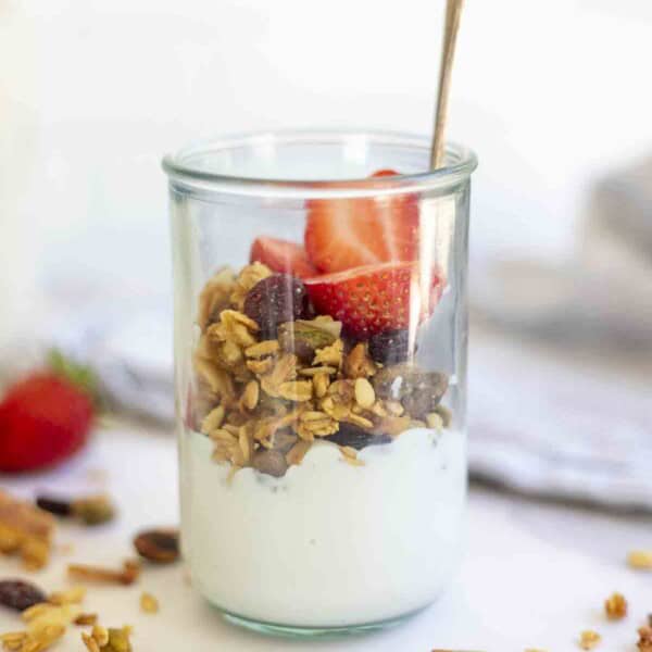 sourdough granola on top of yogurt in a glass jar.