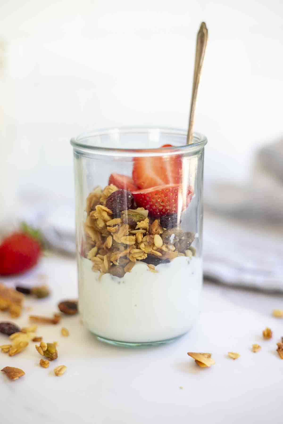 sourdough granola on top of yogurt in a glass jar.