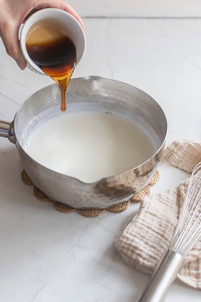 Maple syrup being poured into a saucepan of milk. 