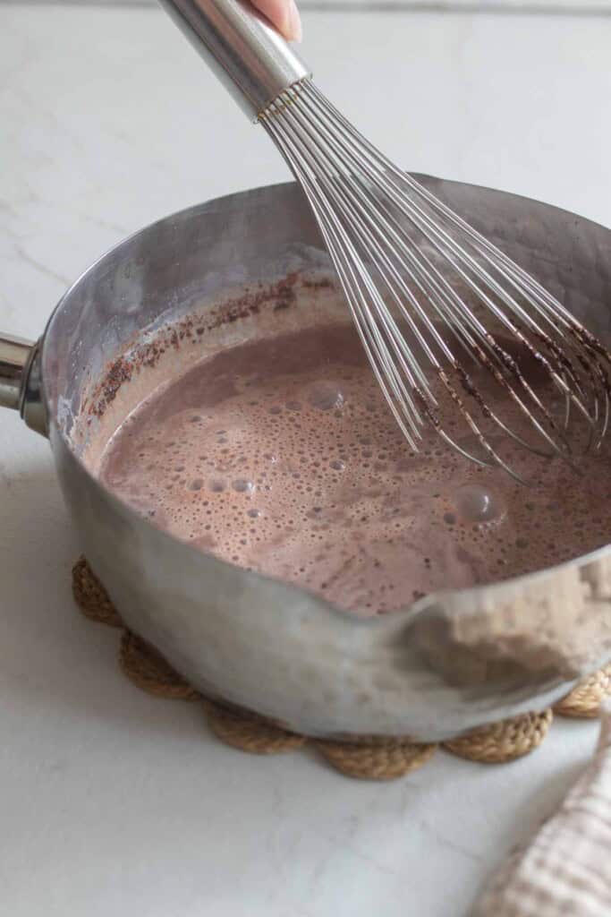 A whisk in a saucepan of hot chocolate. 