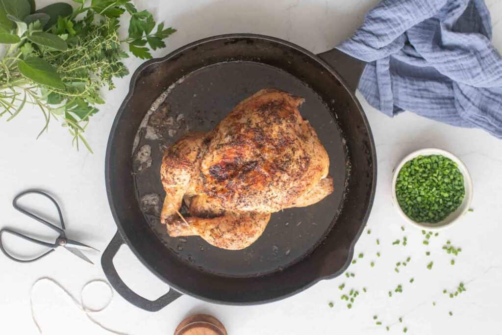 A roasted chicken in a cast iron skillet.