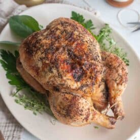 A roasted whole chicken on a white platter.